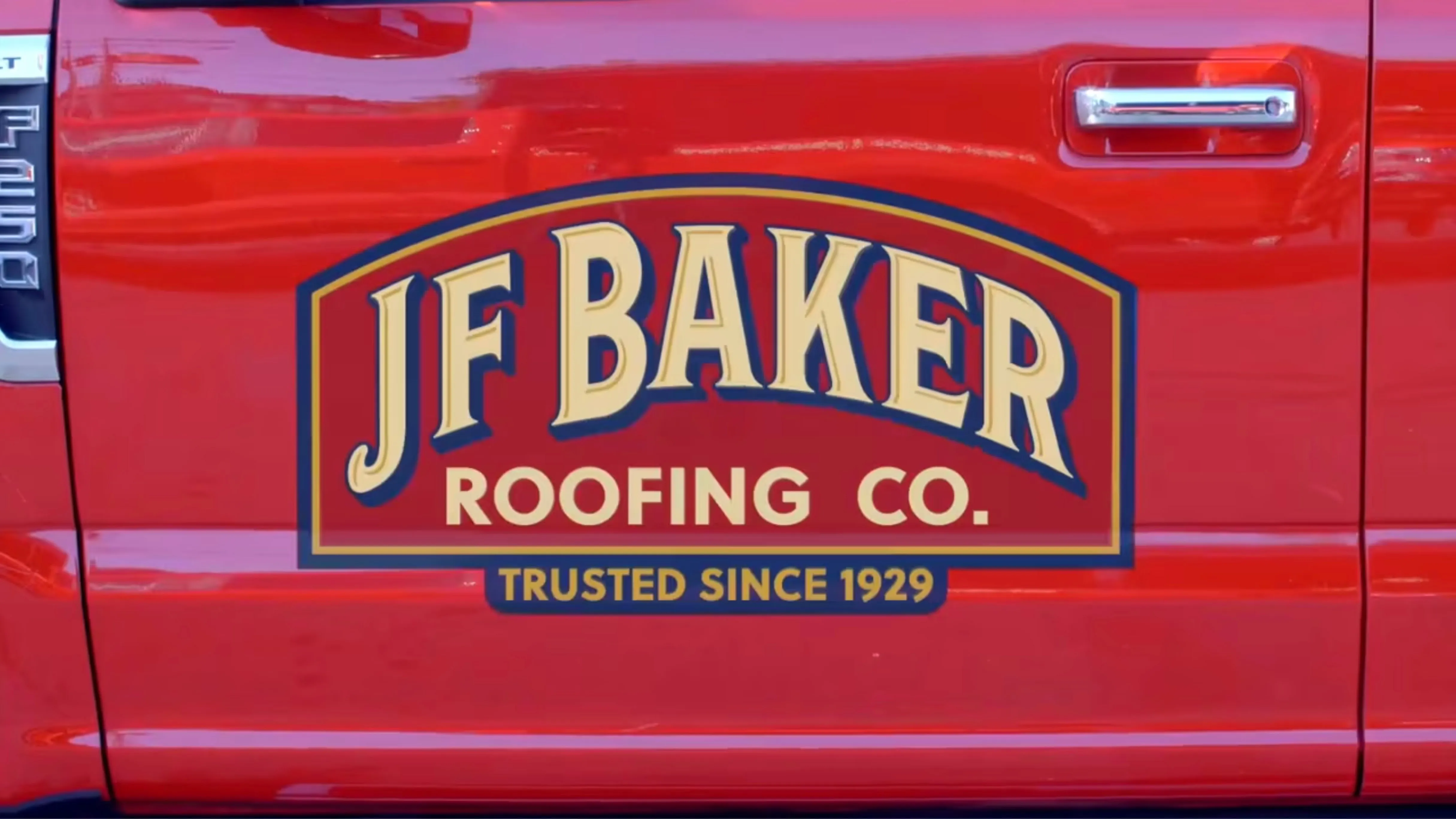 Red truck door with JF Baker Roofing Co. logo and text reading Trusted Since 1929.