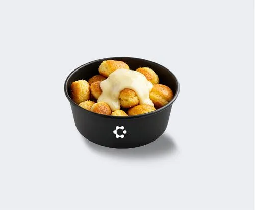 A black bowl with green soup topped with croutons and herbs, featuring a white Circus icon on the front.