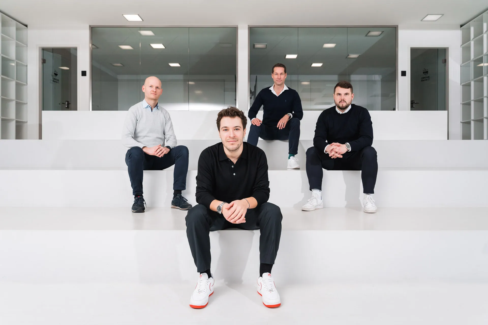 Four executive board members of Circus seated in a minimalistic, modern white office space.