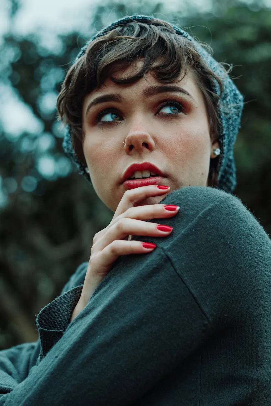 Portrait of a woman wearing a gray beanie and dark clothing, looking to the side with red nail polish visible on her hand.