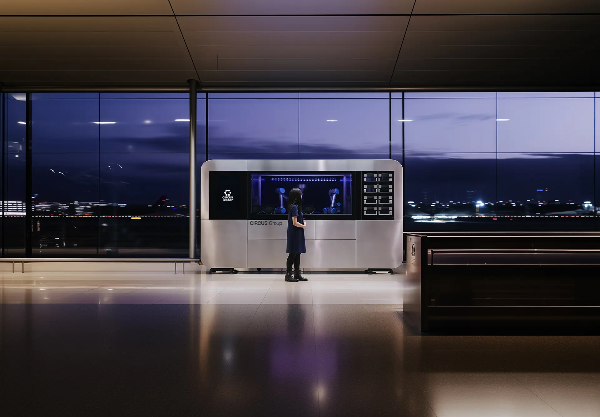 CA-1 Series 4 robotic kitchen installed in a modern airport terminal, with a woman interacting with the machine against a twilight cityscape backdrop.