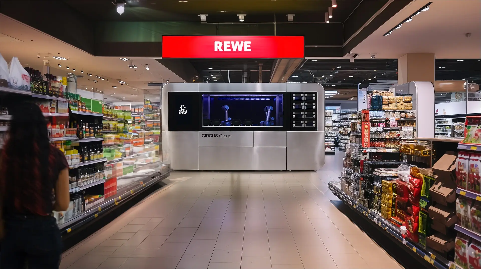 Circus Group's CA-1 Series 4 robotic cooking system installed inside a REWE supermarket, integrated between grocery aisles for on-site fresh food preparation.
