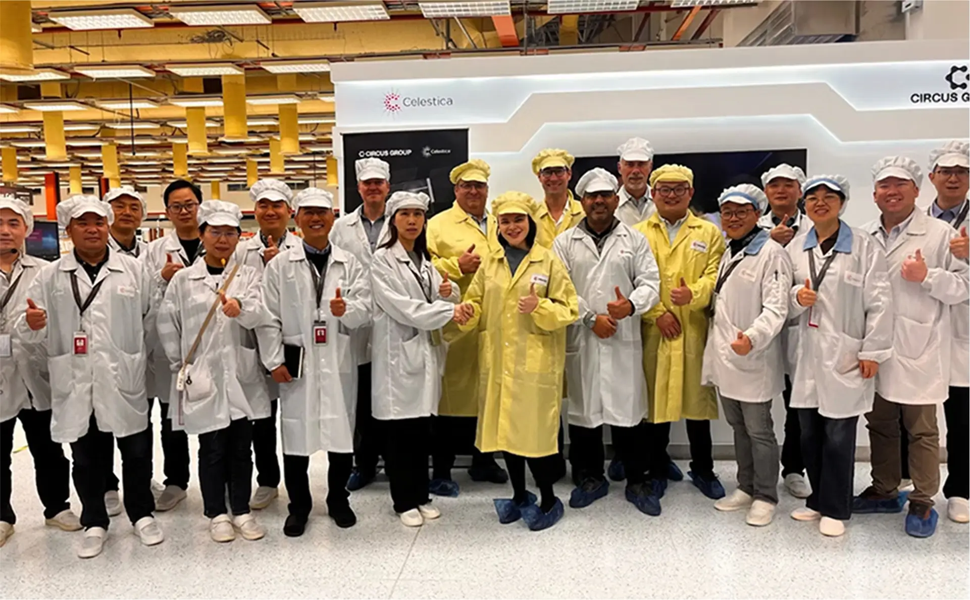 Circus team and Celestica staff wearing cleanroom attire, posing together in front of a CA-1 unit, symbolizing a global production and service partnership.