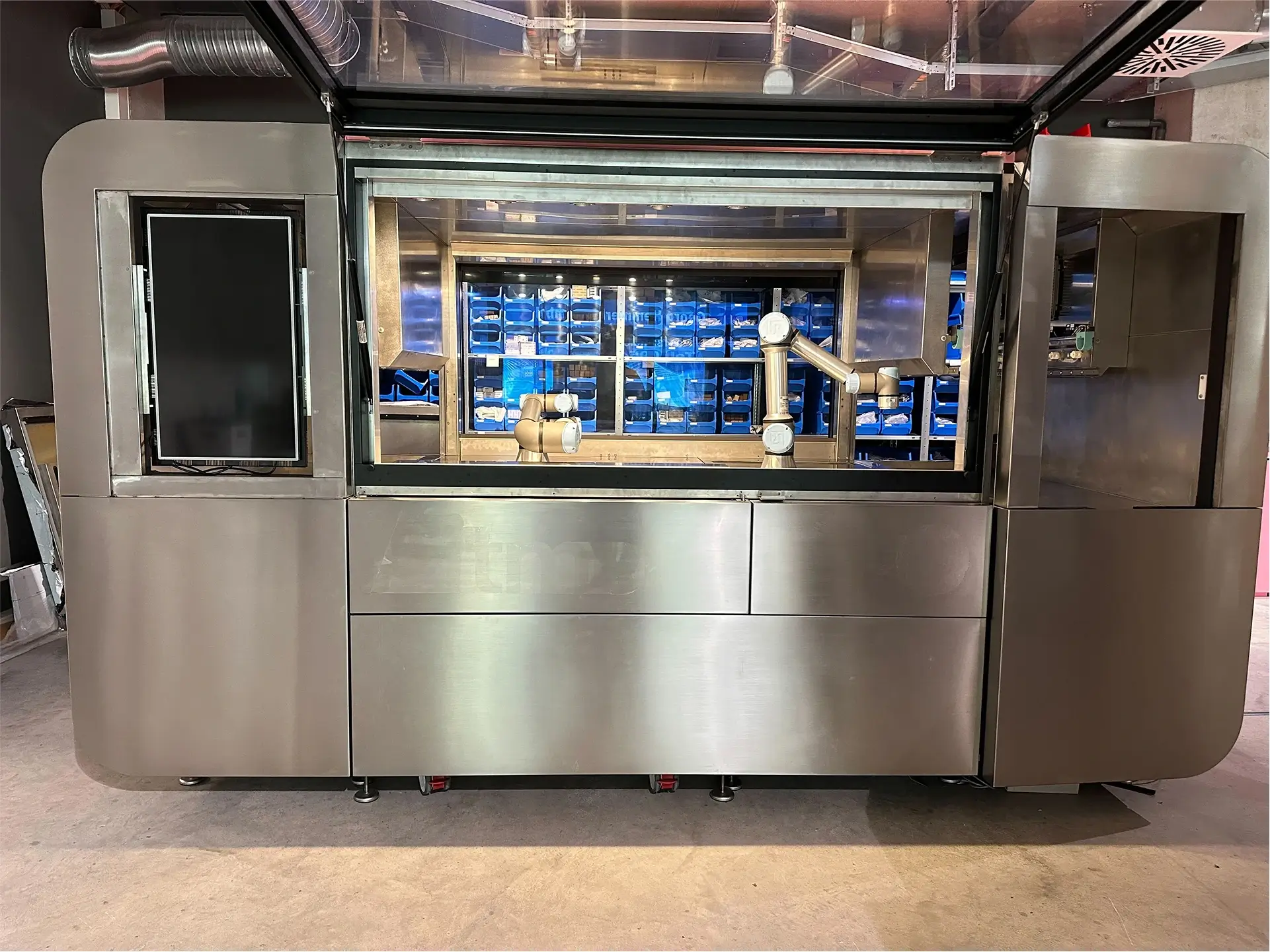 CA-1 unit in a controlled indoor environment undergoing continuous testing and development, featuring visible robotic arms and organized component bins in the background.