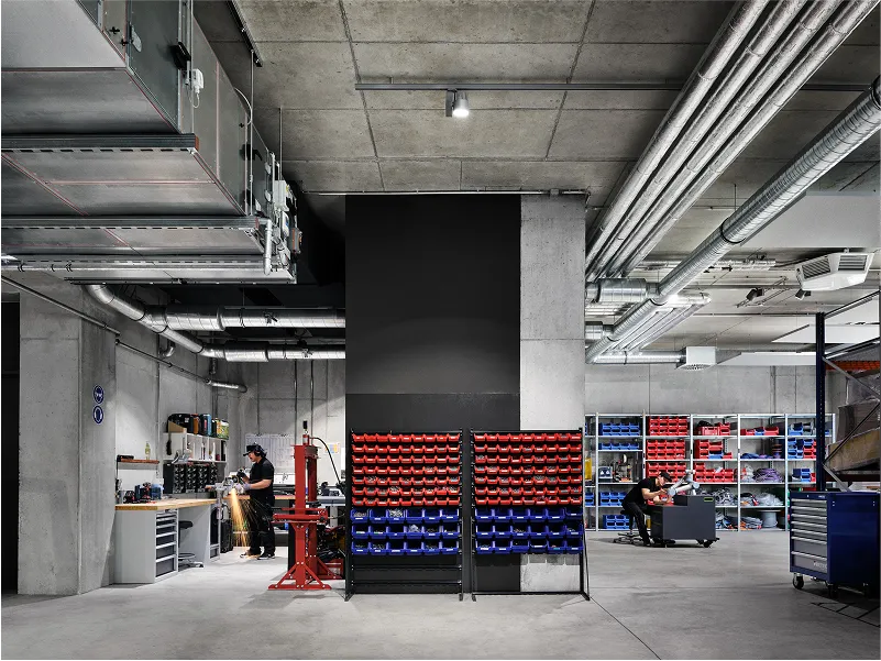 Industrial workspace with organized tool racks, workbenches, and technicians working in a modern, accessible environment.
