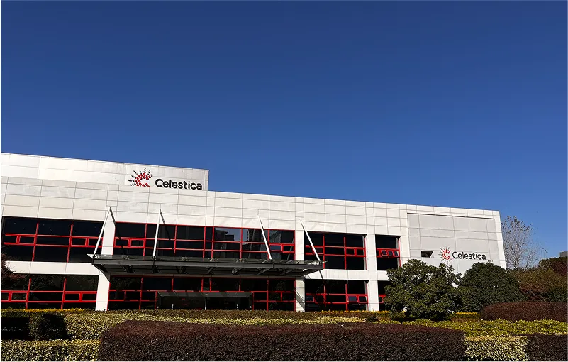 Exterior view of the Celestica building in Suzhou, featuring red-framed windows, a glass entrance canopy, and a clear blue sky.