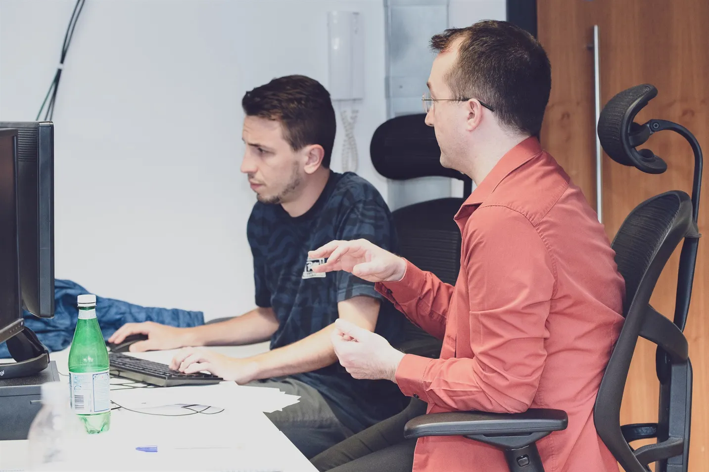 Expert engineers working together at an office desk, in front of a computer