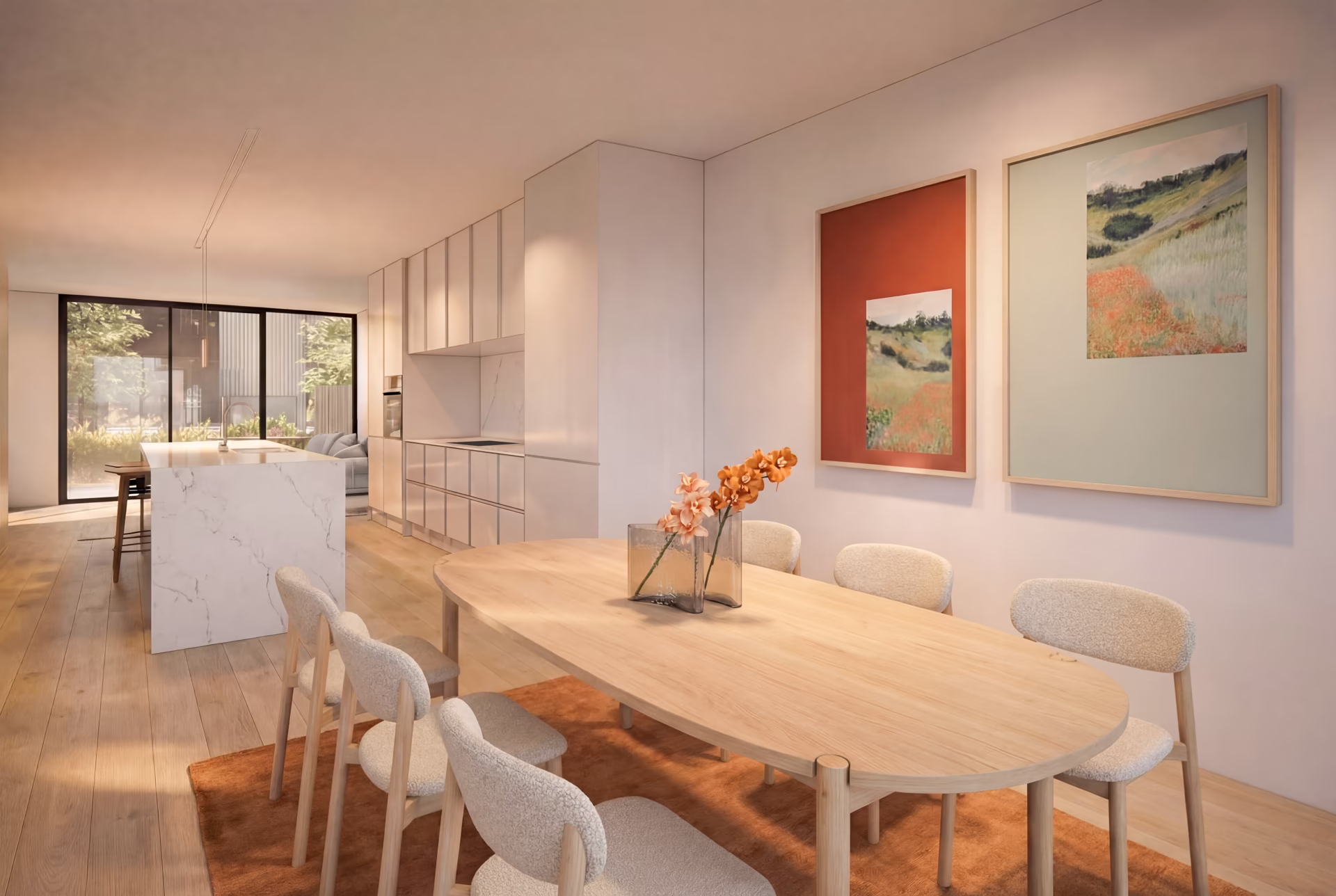 Modern dining area with a light wood oval table, six upholstered chairs, floral centerpiece, and two framed landscape paintings on the wall, next to a sleek white kitchen with marble island and large window.
