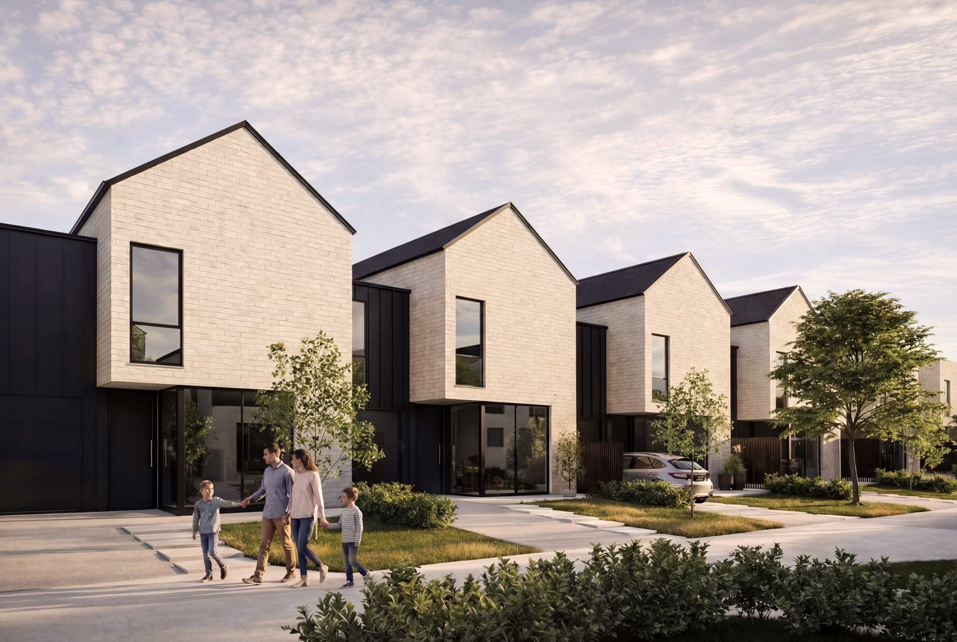 Modern row of cream brick townhouses with black accents and a family walking on the sidewalk in front.