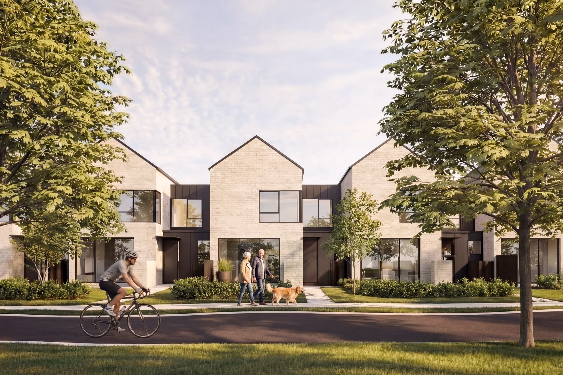 Modern residential townhouses with large windows, landscaped front lawns, a cyclist on the street, and a couple walking a dog on the sidewalk.
