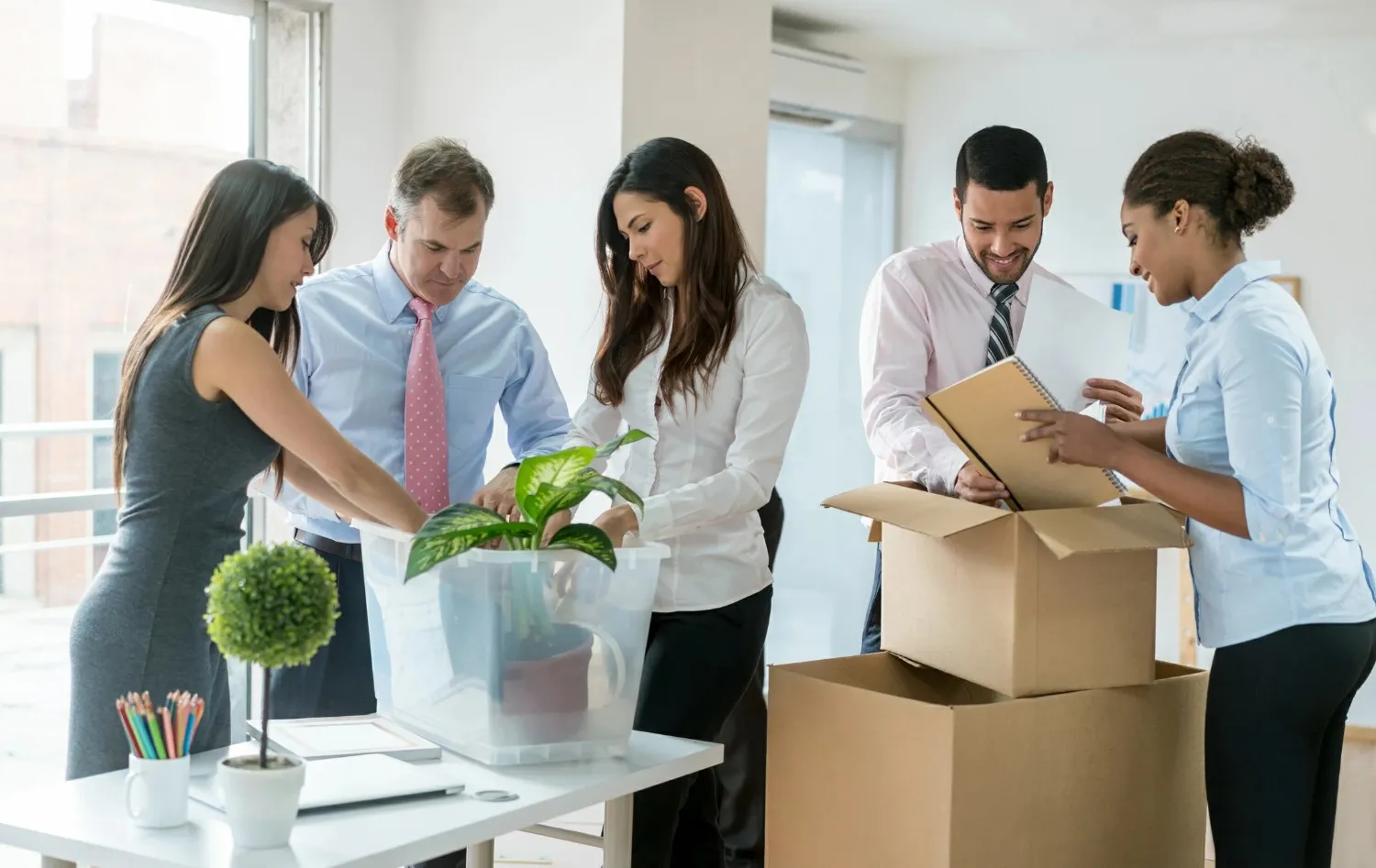 Diverse office team packing relocation boxes.
