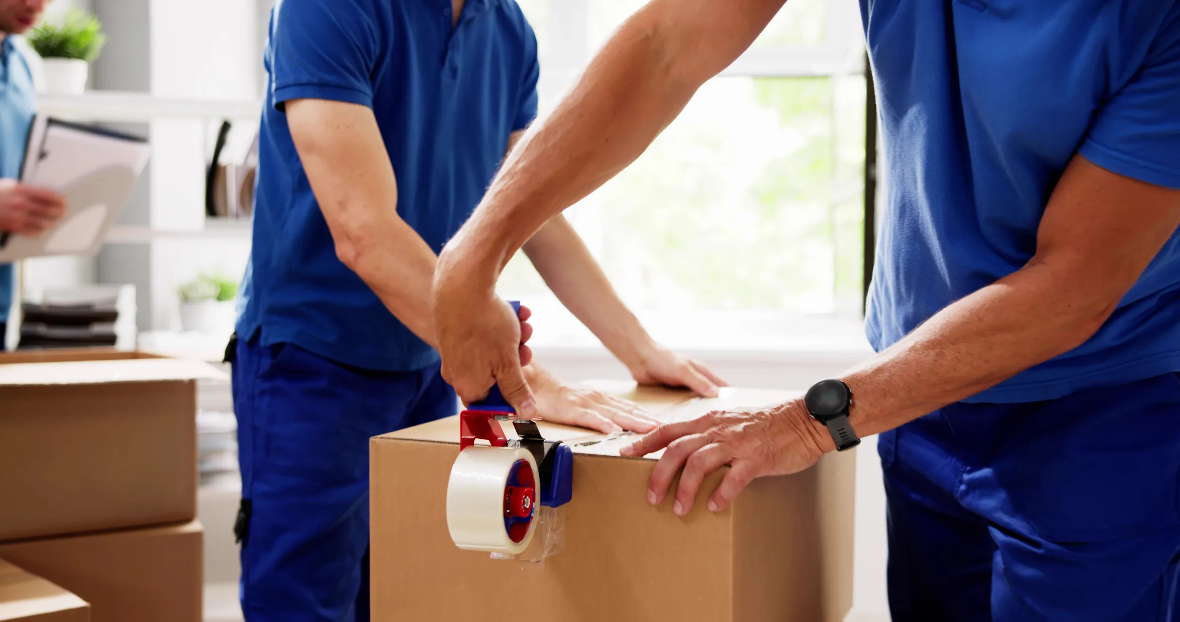 Movers packing and taping boxes together during a professional relocation