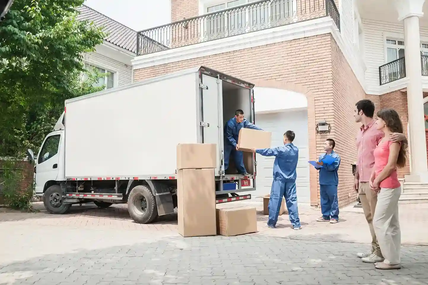Professional movers unloading boxes from a moving truck at a residential home