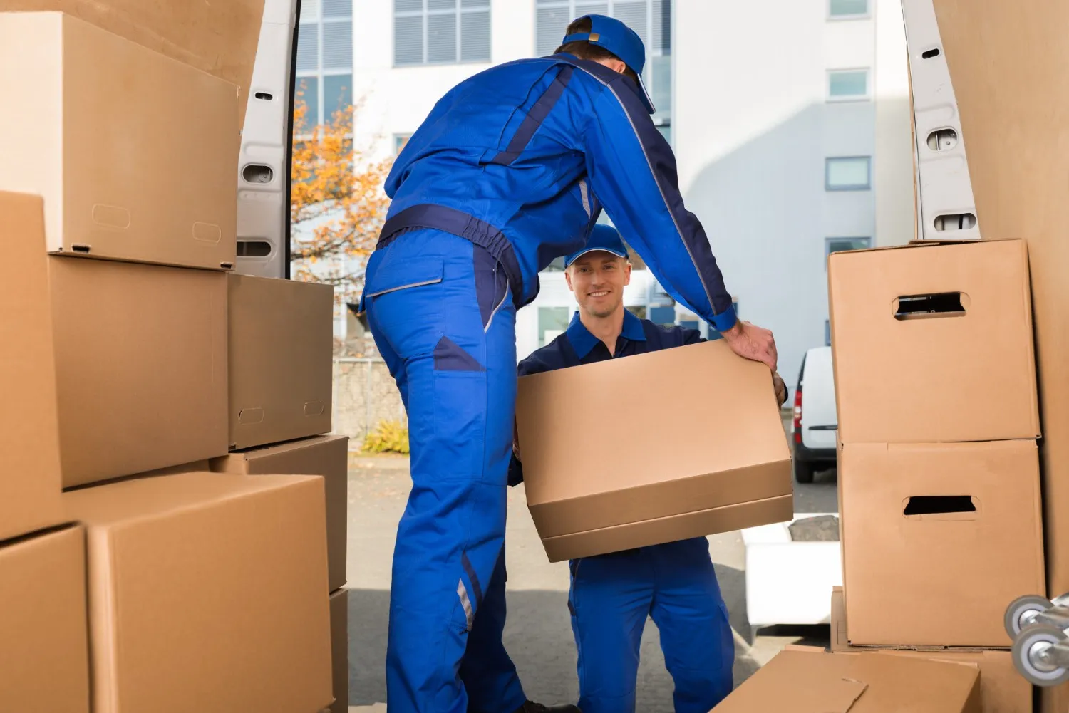 Movers loading cardboard boxes into van.