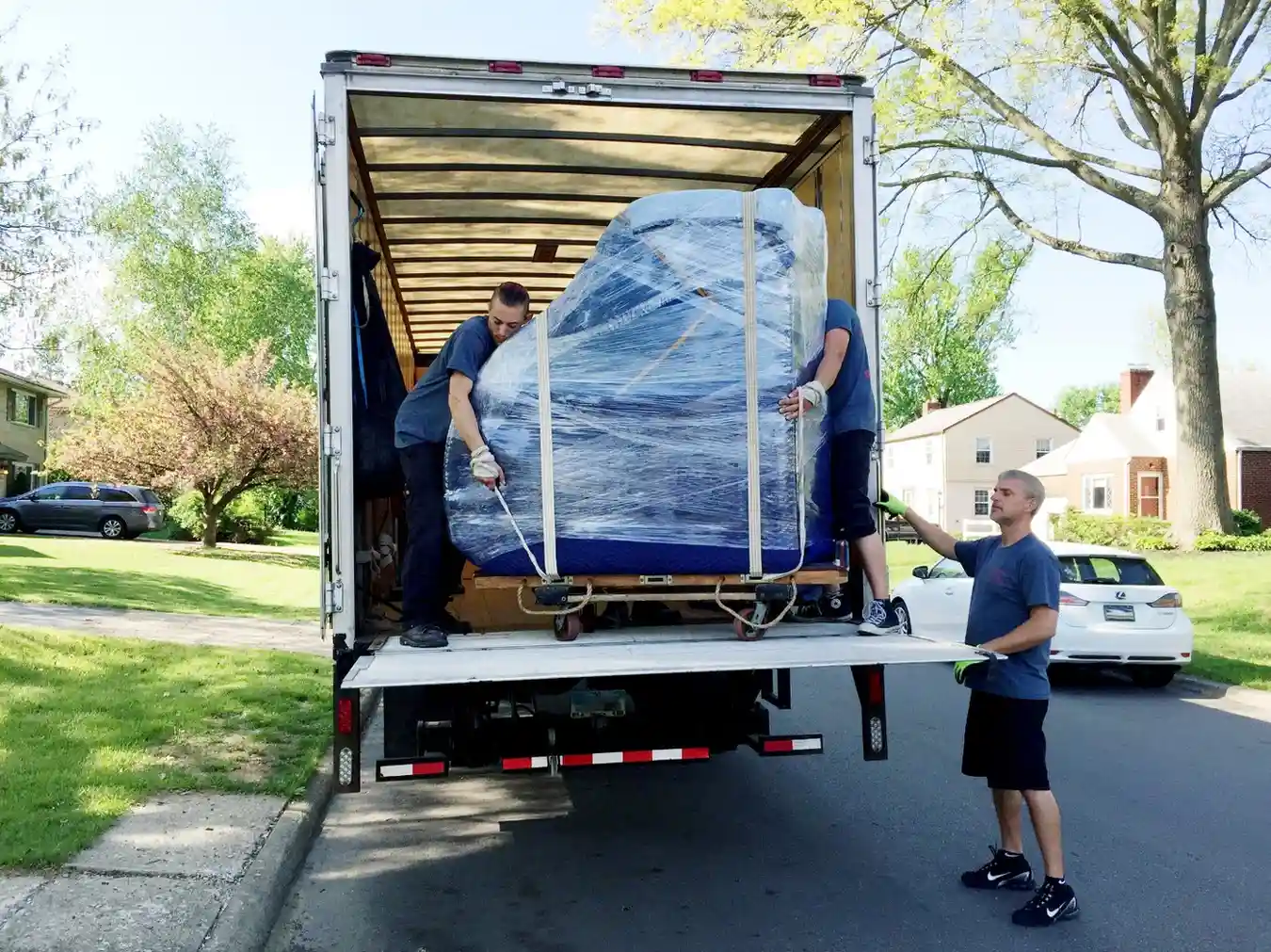 Movers loading wrapped piano into truck.