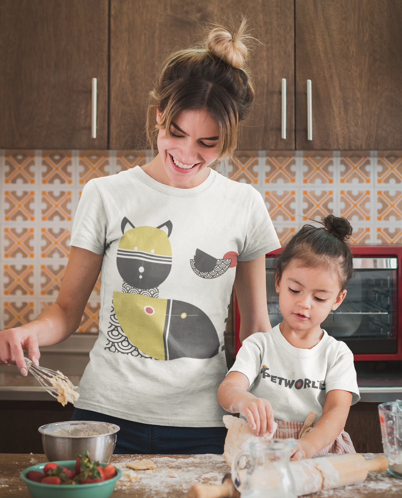 Smiling woman and young girl in white t-shirts baking together in a kitchen with flour and dough on the counter.