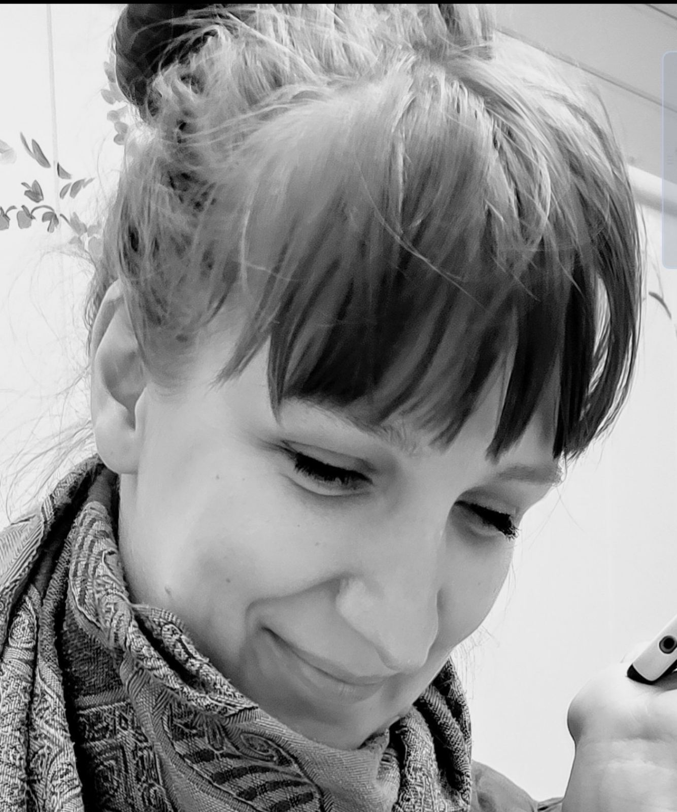 Close-up black and white photo of a woman smiling gently with closed eyes, wearing a patterned scarf.