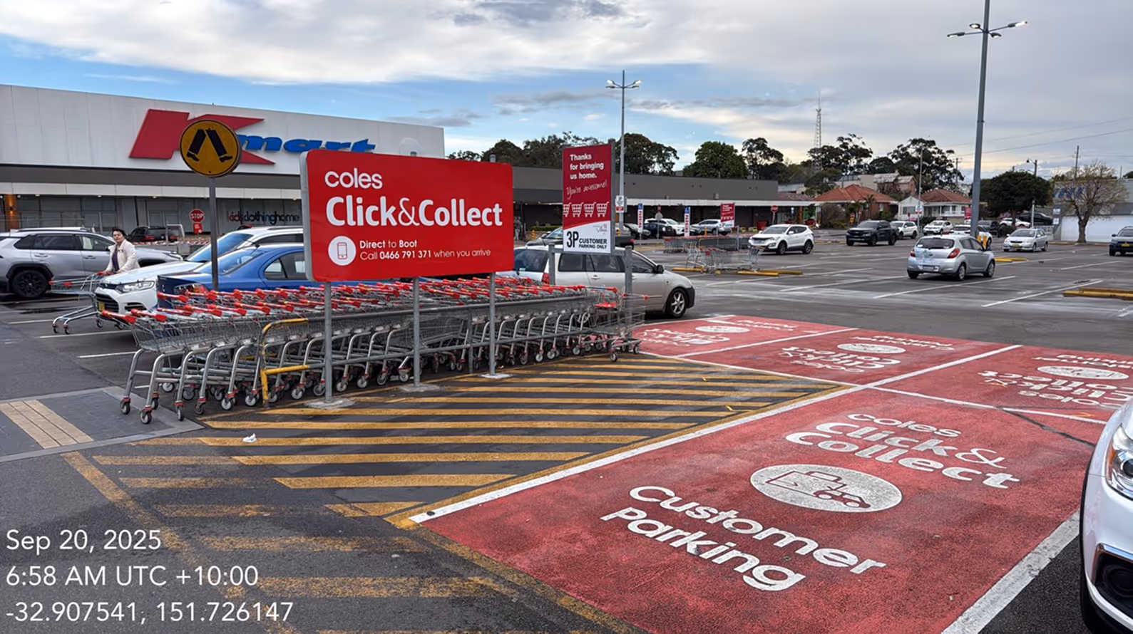 Coles supermarket parking lot showing Coles Click & Collect customer parking spaces marked in red with shopping carts nearby and cars parked around.