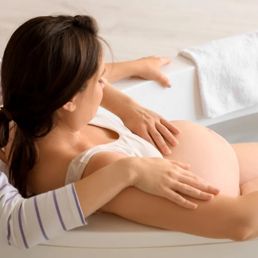 Eine schwangere Frau liegt entspannt in der Badewanne und wird liebevoll von einer Doula begleitet – Symbol für Geborgenheit, Vertrauen und achtsame Geburtsbegleitung bei Cozyfamily in Magdeburg.