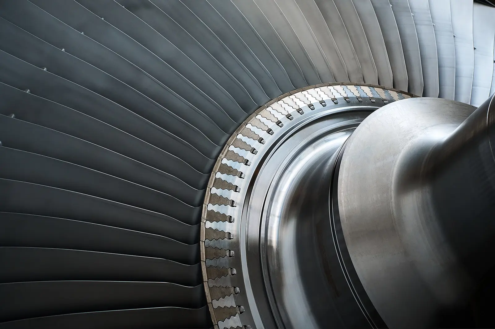 Nahaufnahme der glänzenden, metallischen Schaufeln eines industriellen Laufrads oder einer Turbine mit einem blau lackierten Gehäuseteil im Vordergrund.