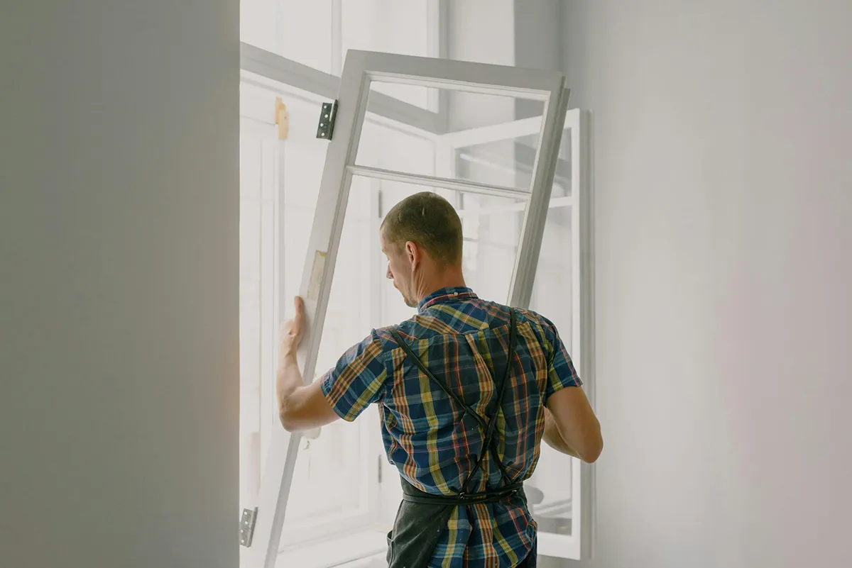 Menuisier installant une fenêtre PVC blanche dans un logement