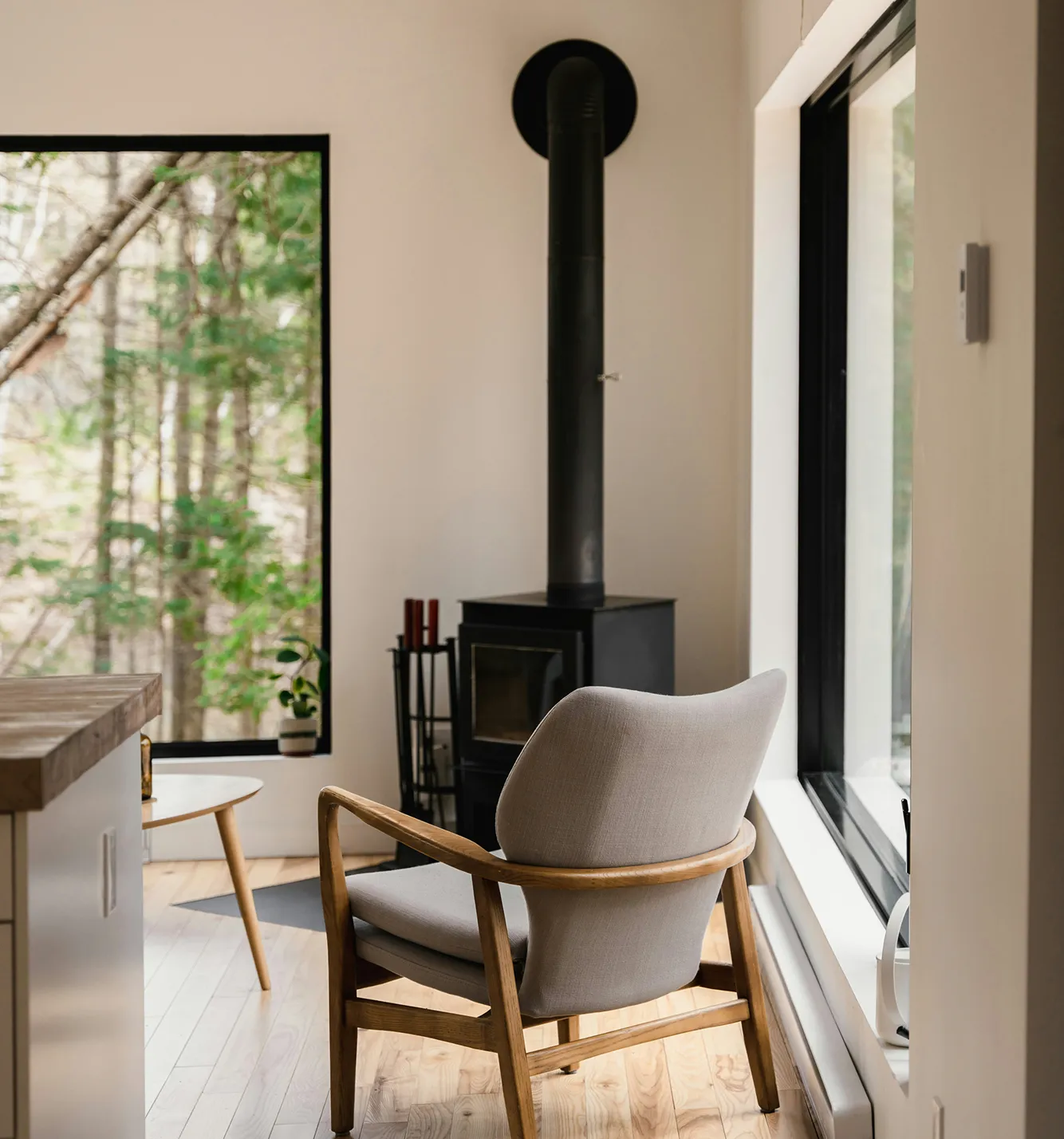Intérieur avec poêle à bois et grande fenêtre donnant sur la forêt
