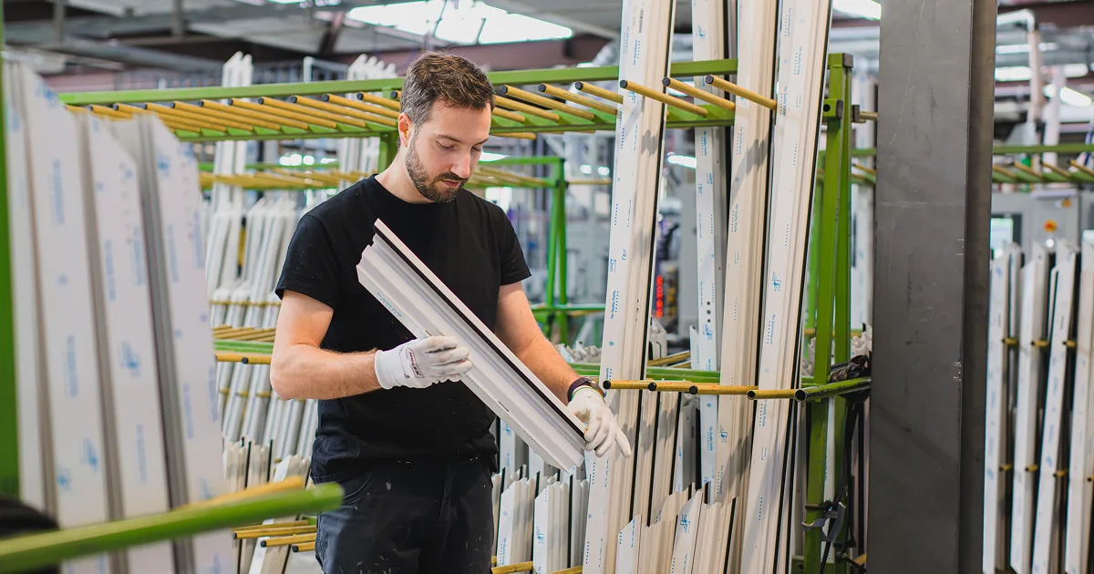 Collaborateur Domofen manipulant des profilés PVC dans l'espace de production