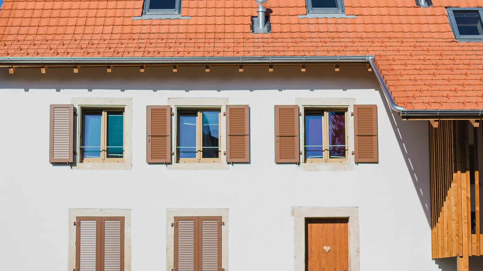Façade rénovée avec fenêtres et volets dans le canton du Jura.