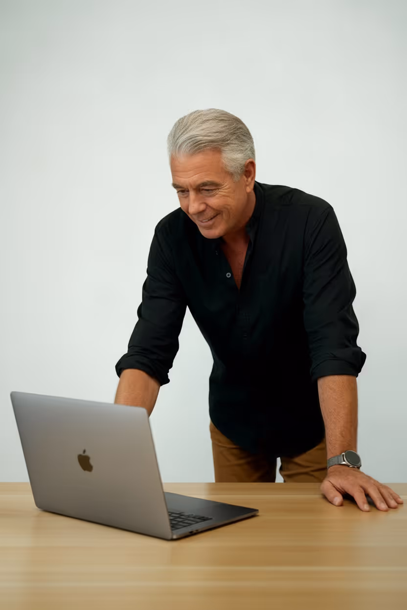 Patrick Noreo, Geschäftsführer von meinMPP, steht mit schwarzem Hemd lächelnd am Schreibtisch vor Computer.