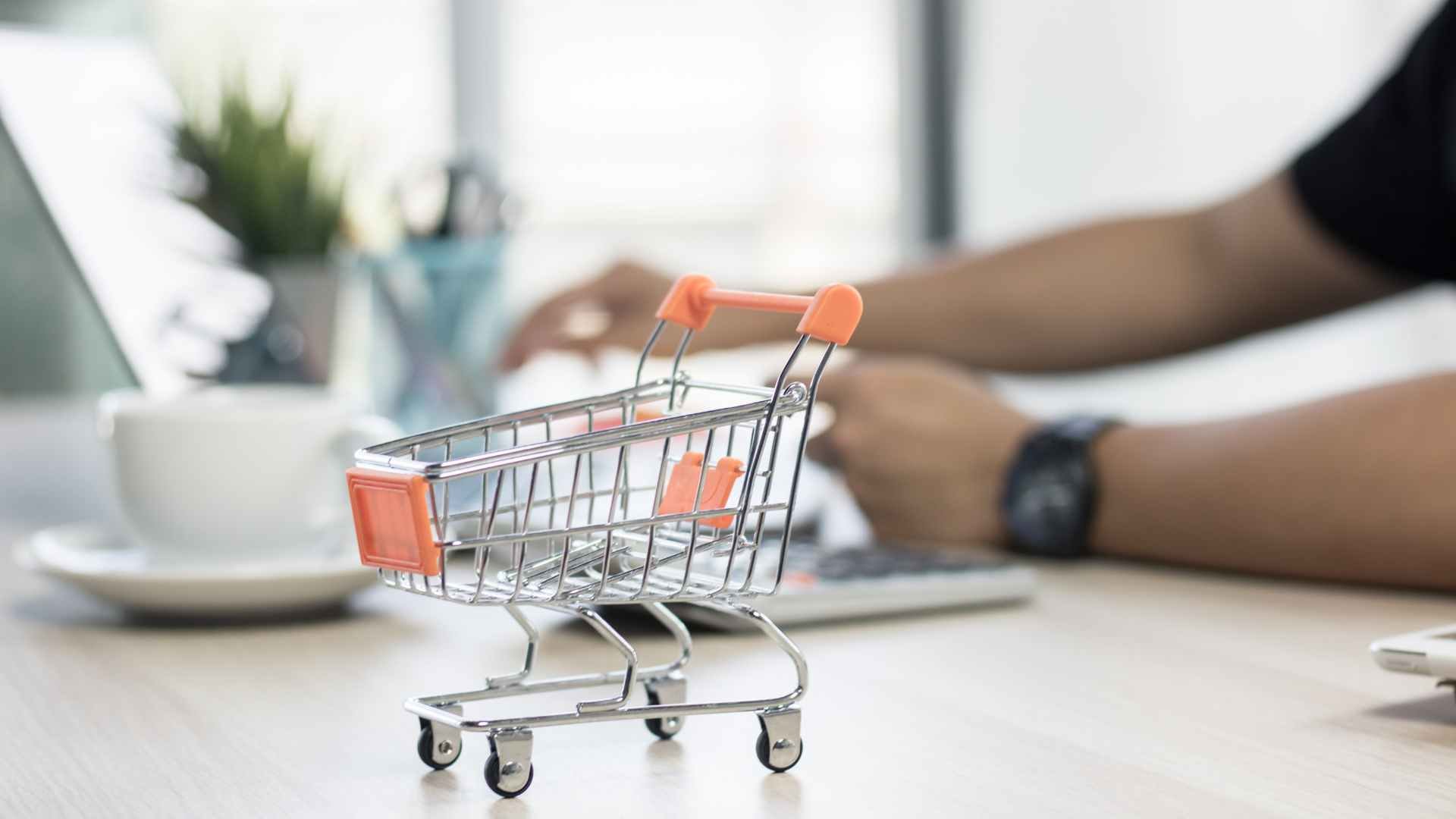 Mini chariot de supermarché sur un bureau symbolisant la formation commerce et vente