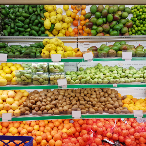 Étal de marché de fruits et légumes bien rangés sur plusieurs étagères.