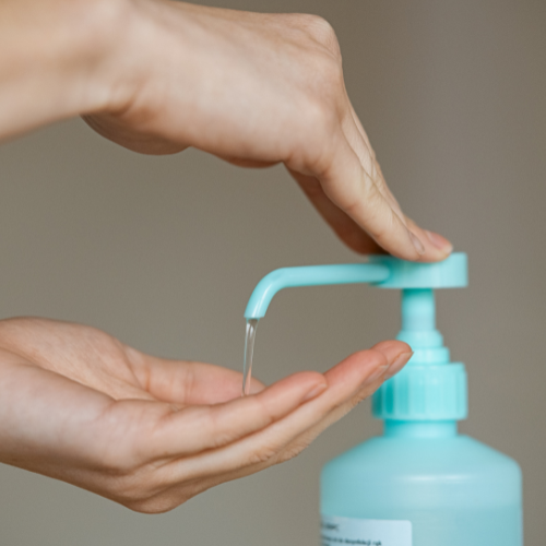 Une main appuie sur une pompe pour distribuer du liquide sur l'autre main ouverte.