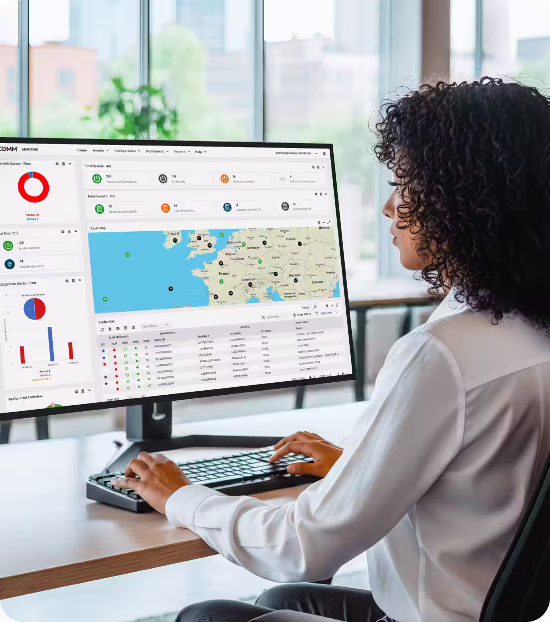 Person using desktop computer displaying a maritime logistics dashboard with map and data charts.