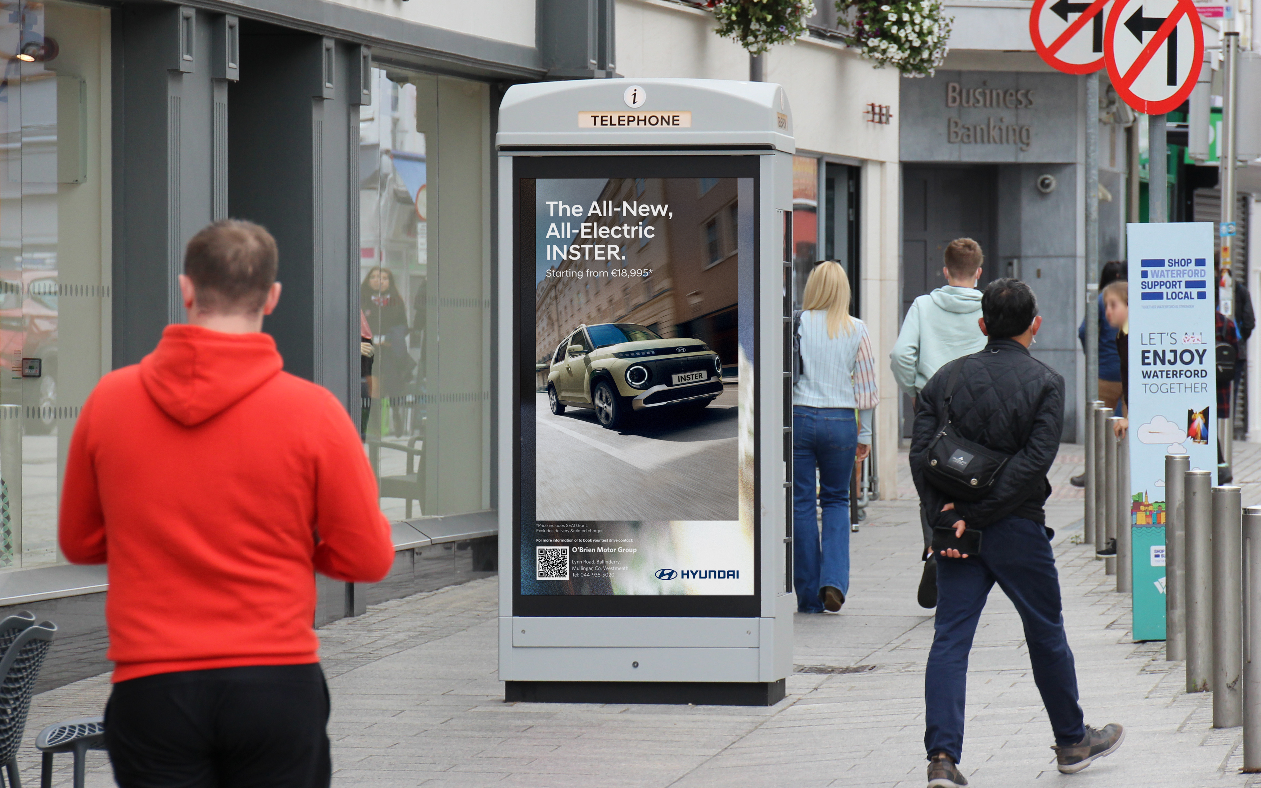 An Adshel Live kiosk on a busy shopping street with people passing by