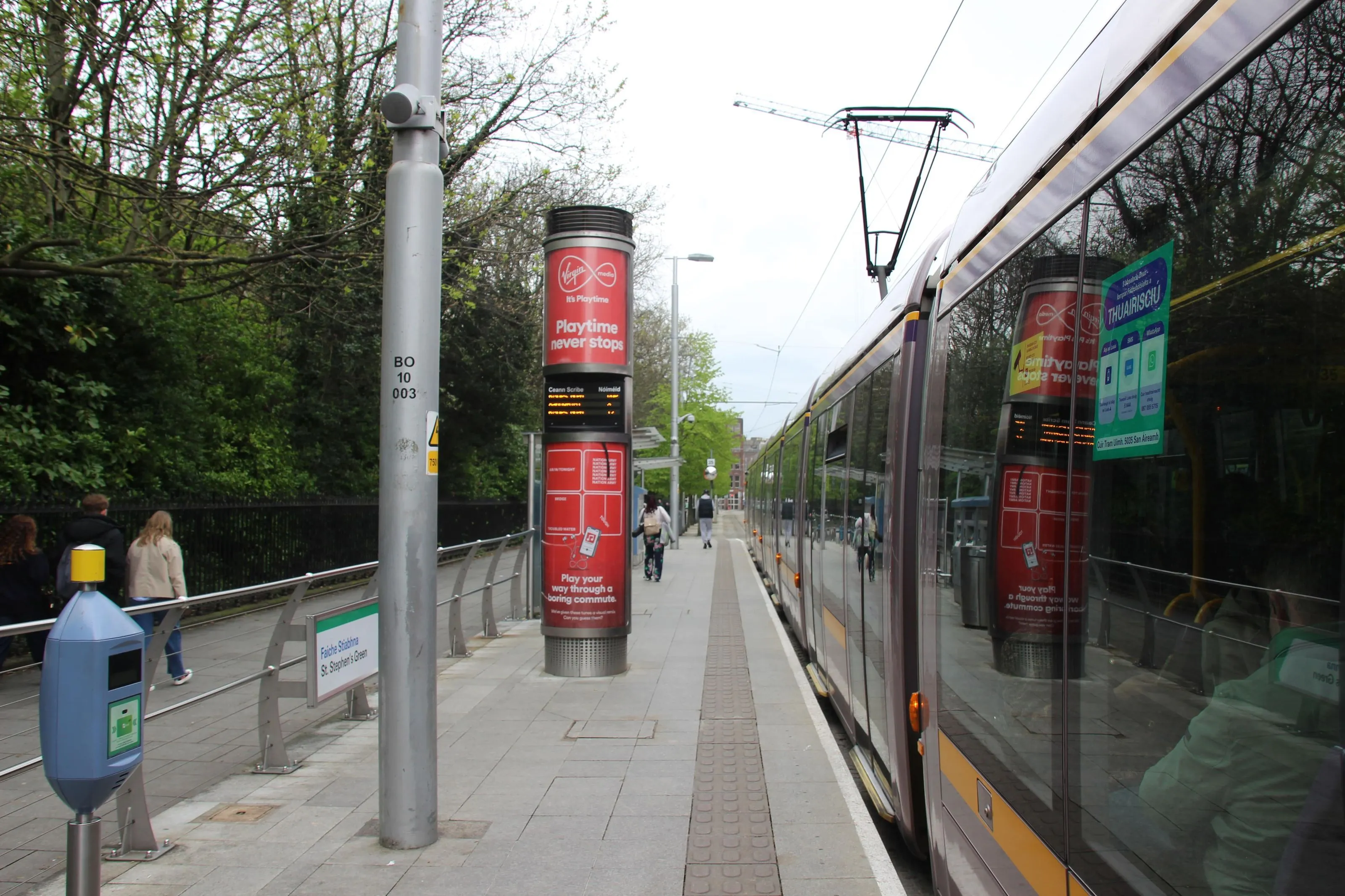 A Luas Column displaying an advertisement for Virgin Media Mobile, situated on the tram platform at St. Stephen's Green