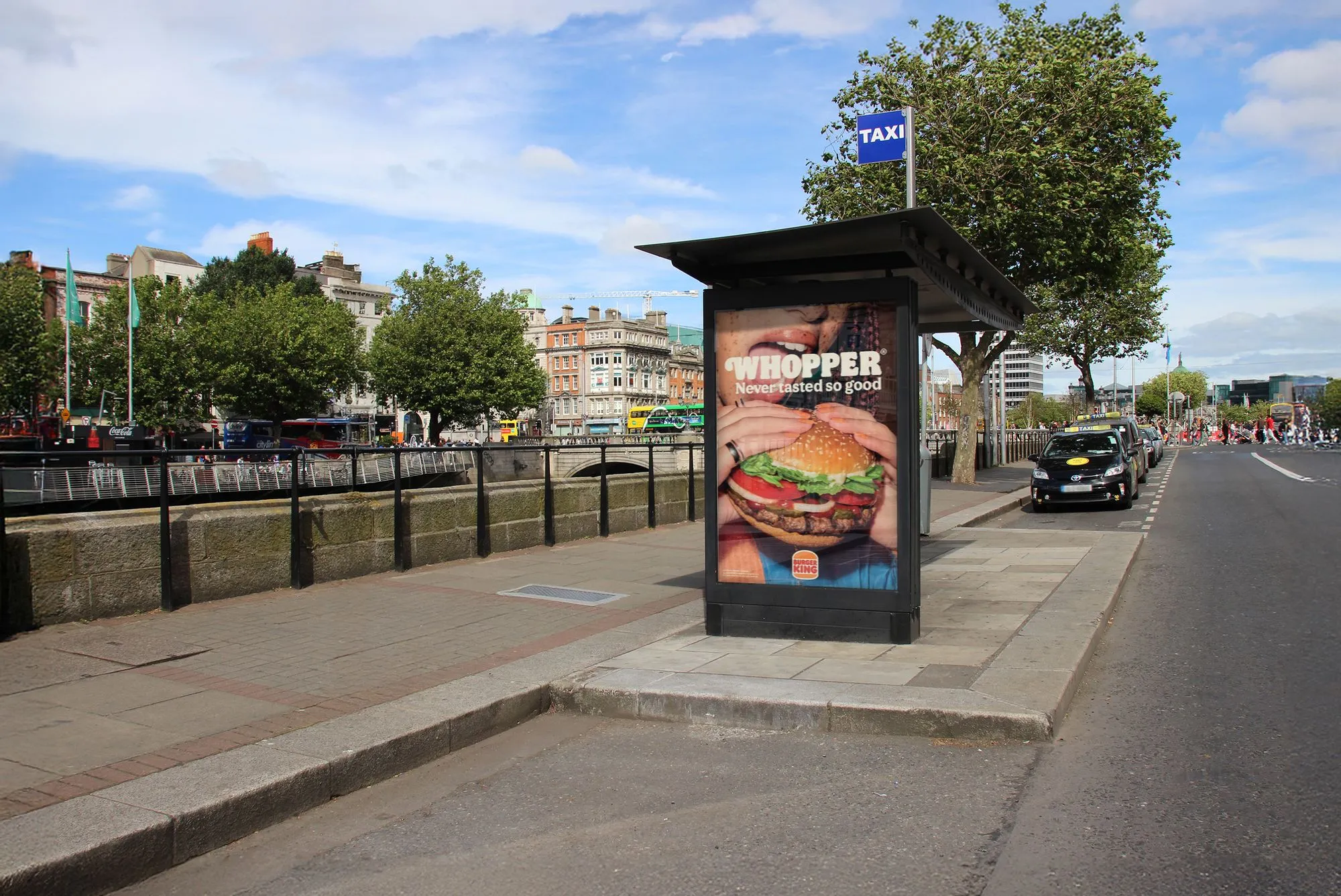 An Adshel taxi shelter displaying an advertisement for Burger King with a view O'Connell Bridge