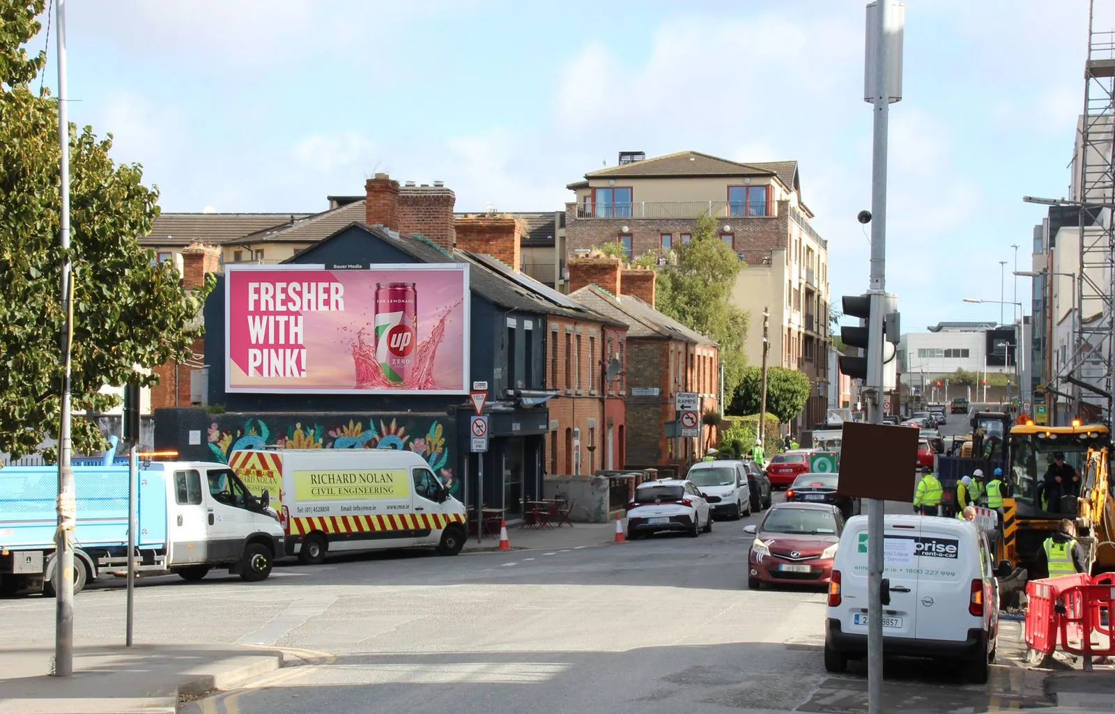 A large billboard advertisement on a busy road, surrounded by trees, businesses and residential homes