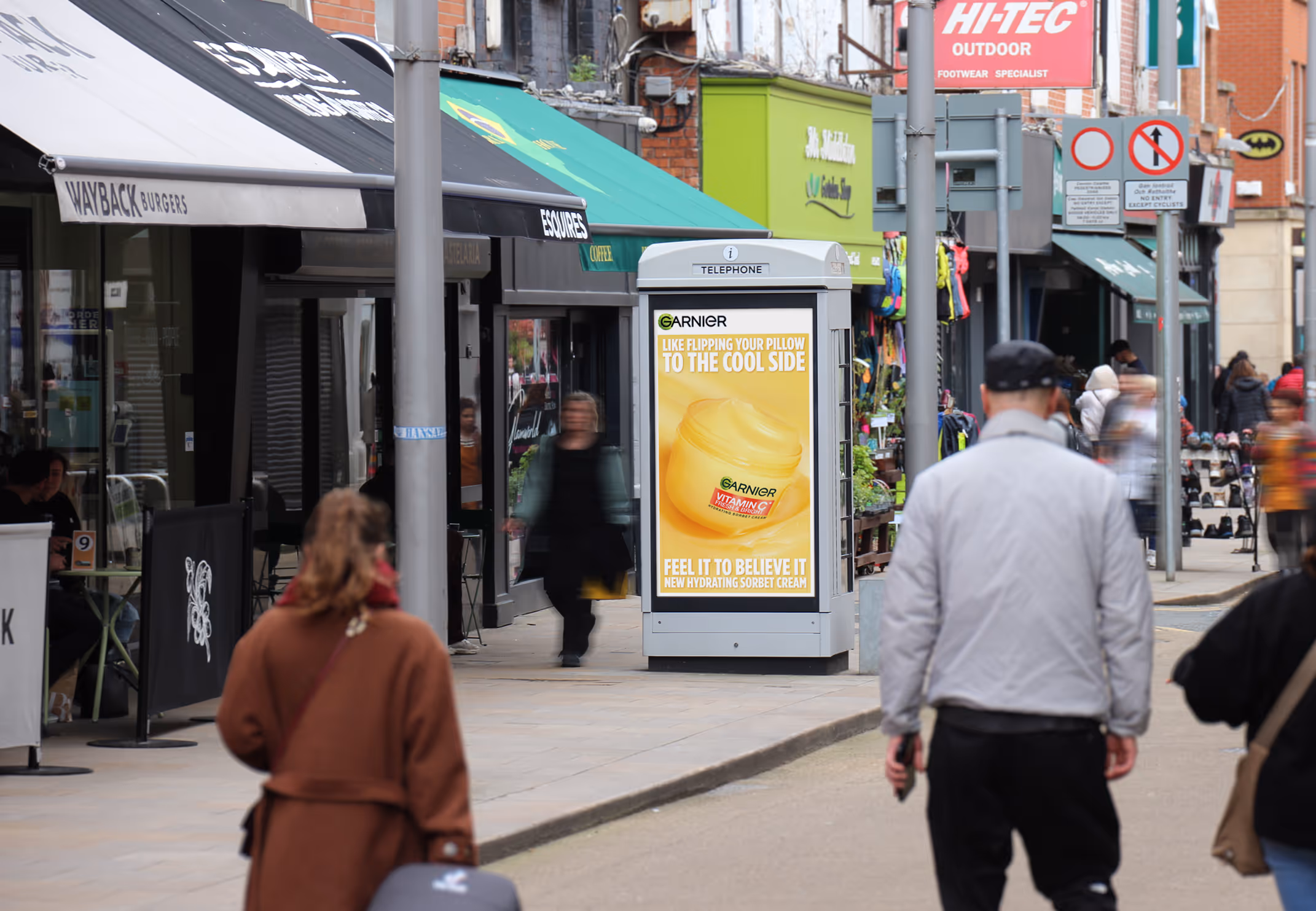 An Adshel Live kiosk displaying an advertisement for Maybelline Sky High mascara, located in a busy retail street in Dublin City centre