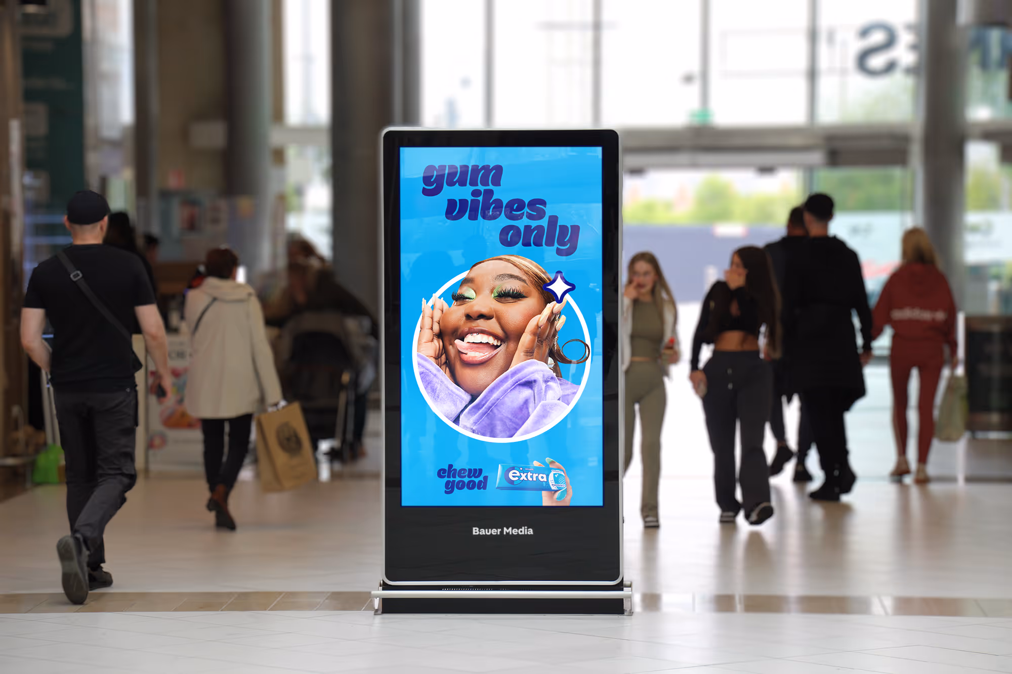 An Adshel Live Retail screen located outside a multiple supermarket displaying an advert for Wrigleys Extra chewing gum