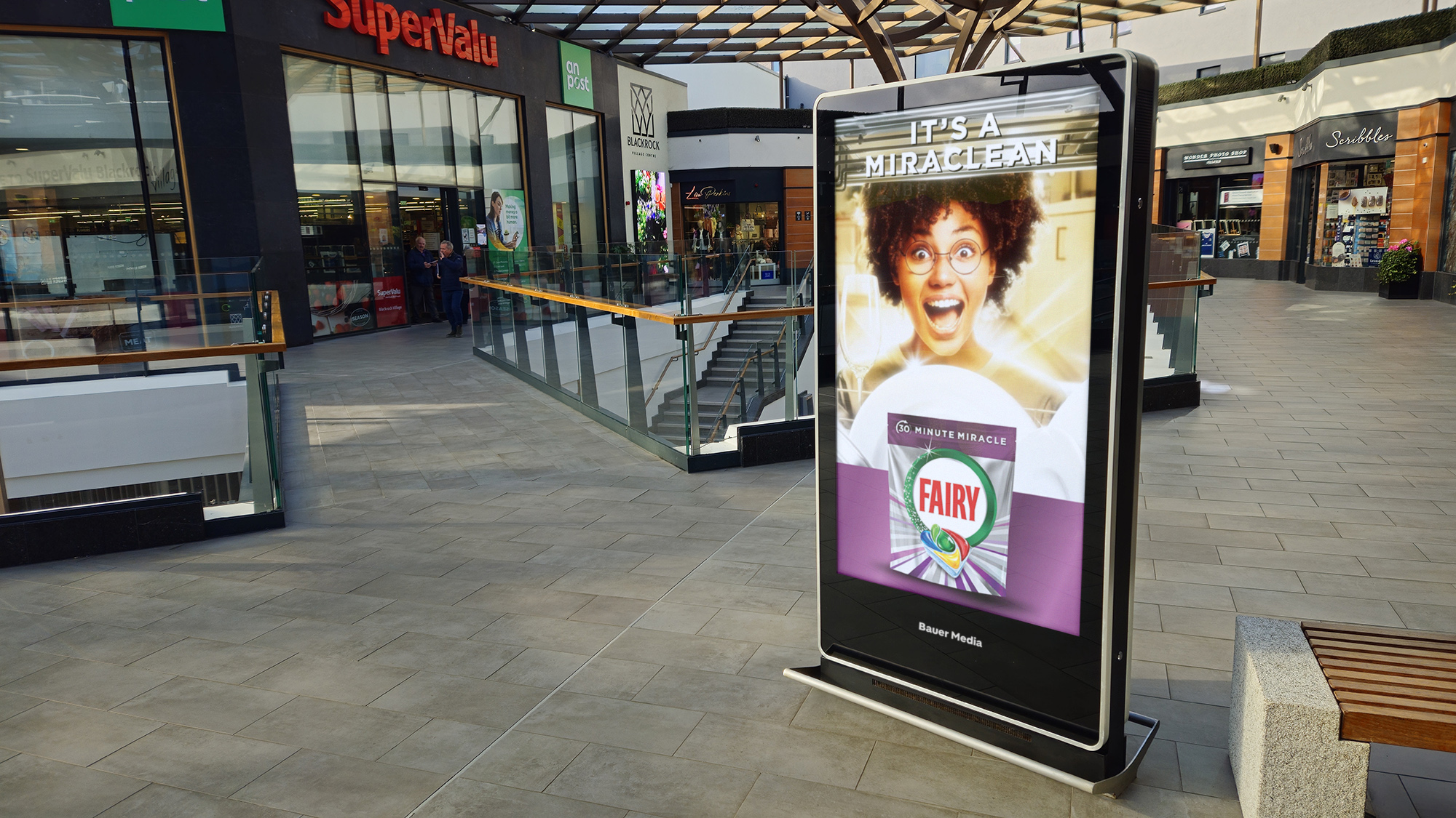 An Adshel Live Retail screen located outside a multiple supermarket displaying an advert for Fairy dishwasher tablets