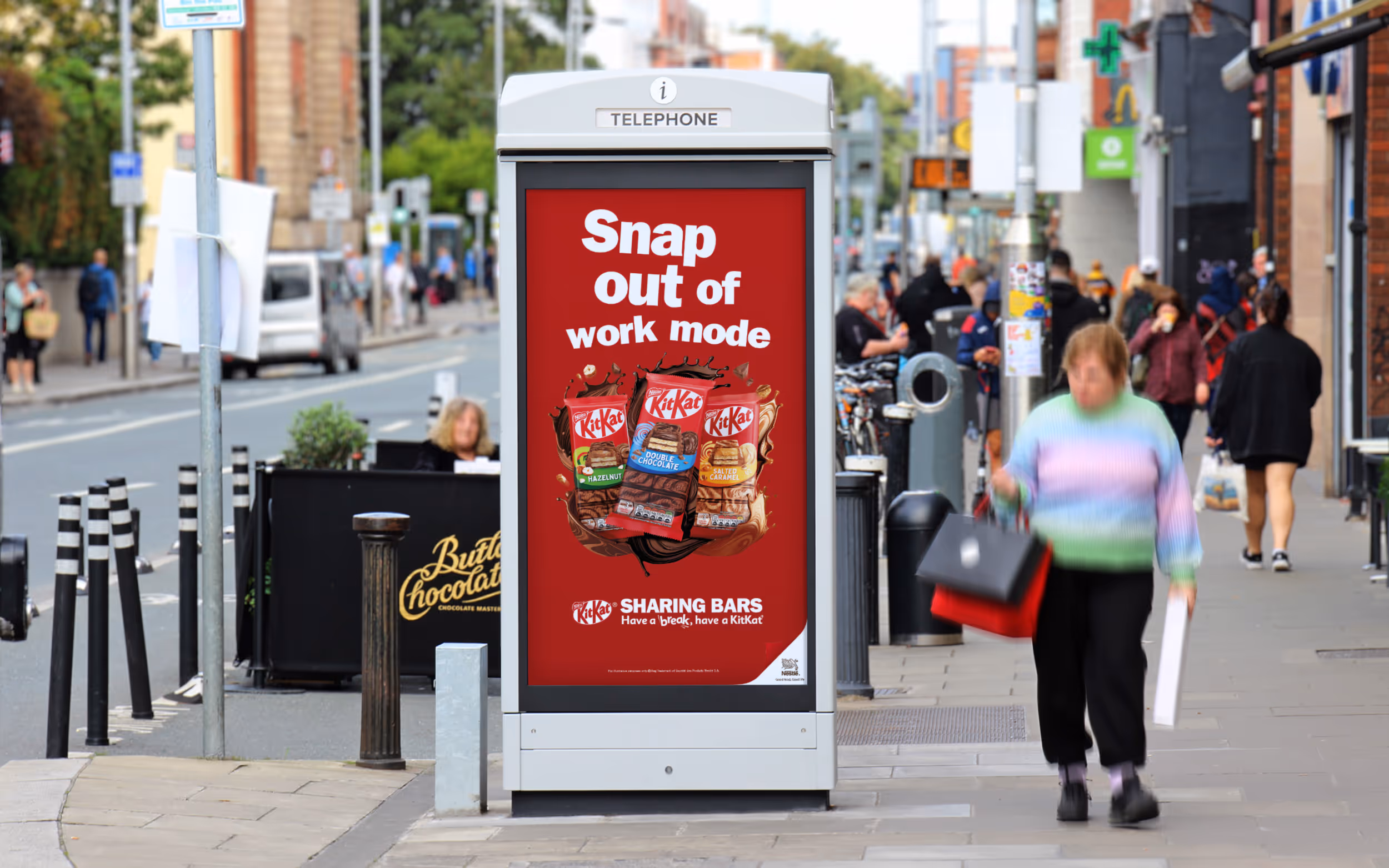 An Adshel Live kiosk on a busy street displaying an advert for KitKat