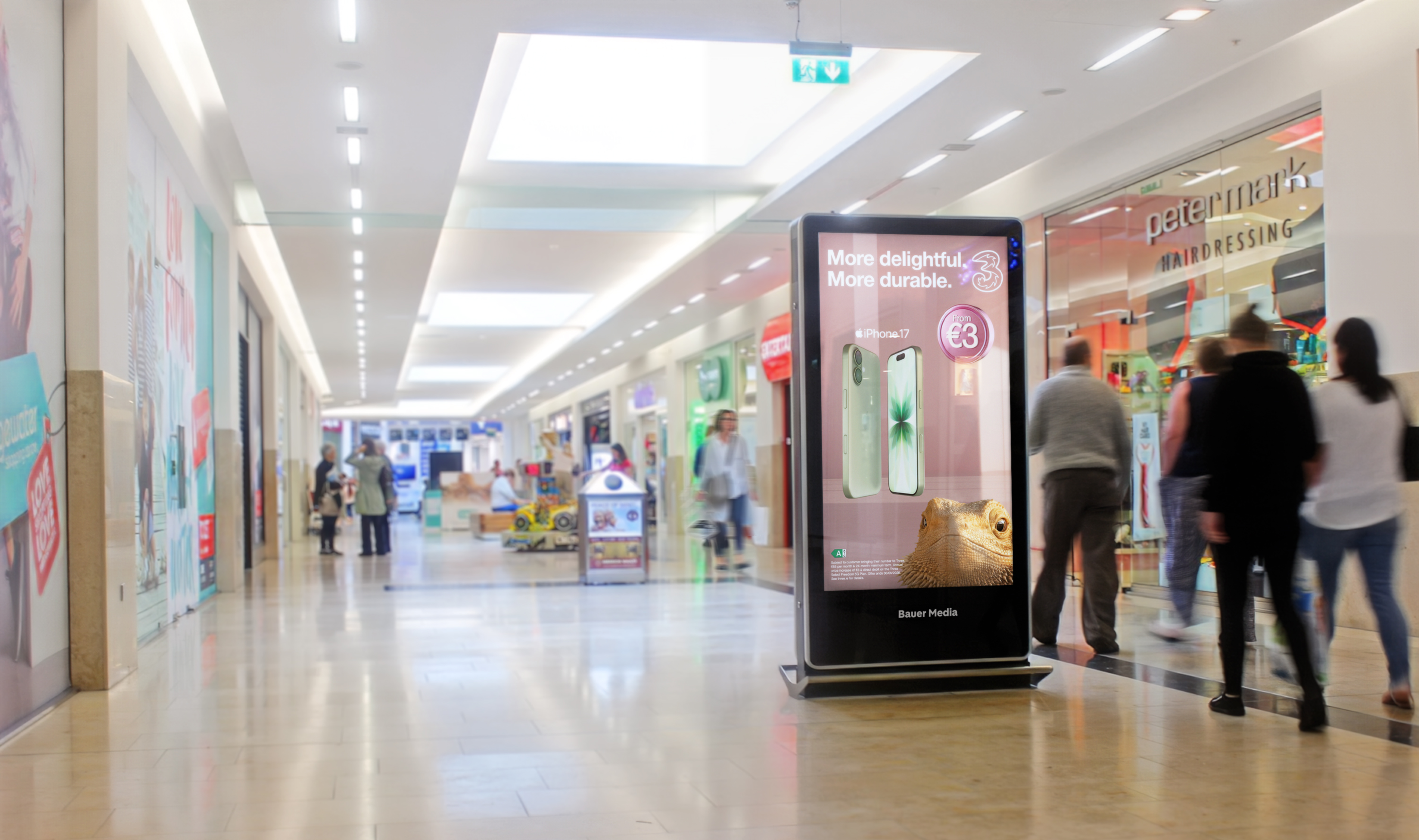 Digital advertisement inside a shopping centre with shoppers walking past