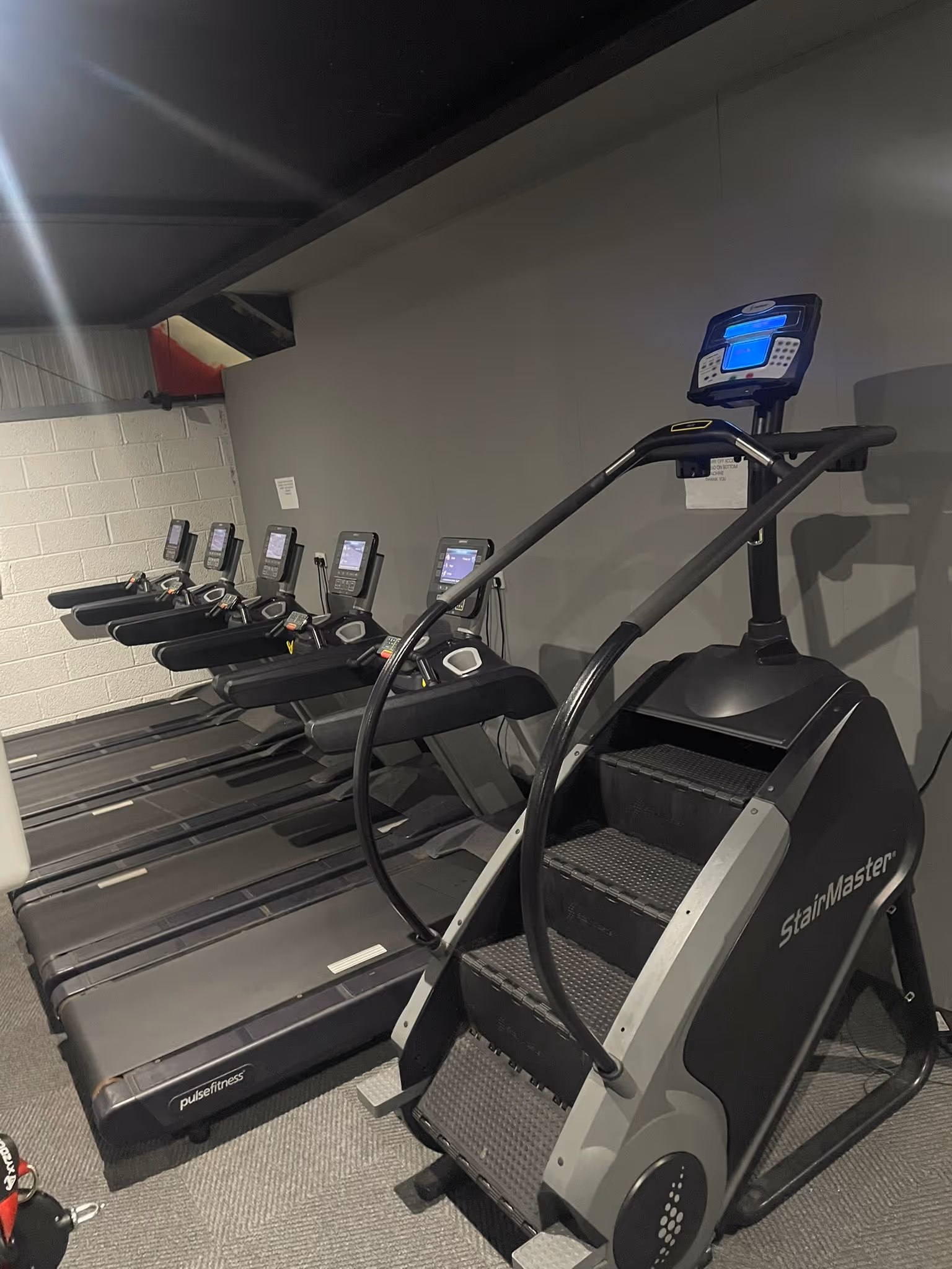 Cardio zone at Magee Health & Fitness Belfast featuring StairMaster and treadmills along the wall
