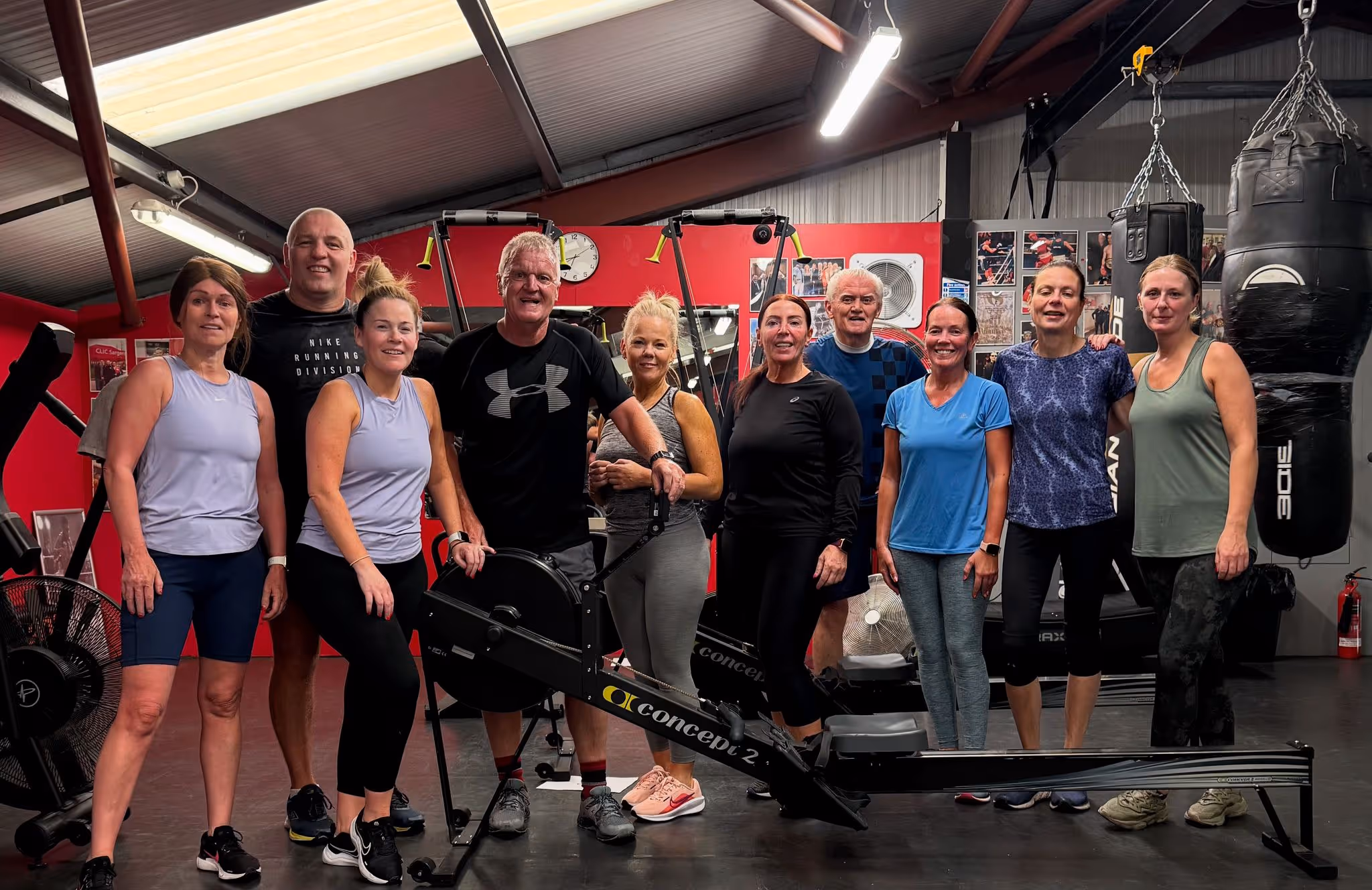 Smiling members after a class at Magee Health & Fitness gym Belfast standing around the Concept 2 rower in the boxing gym