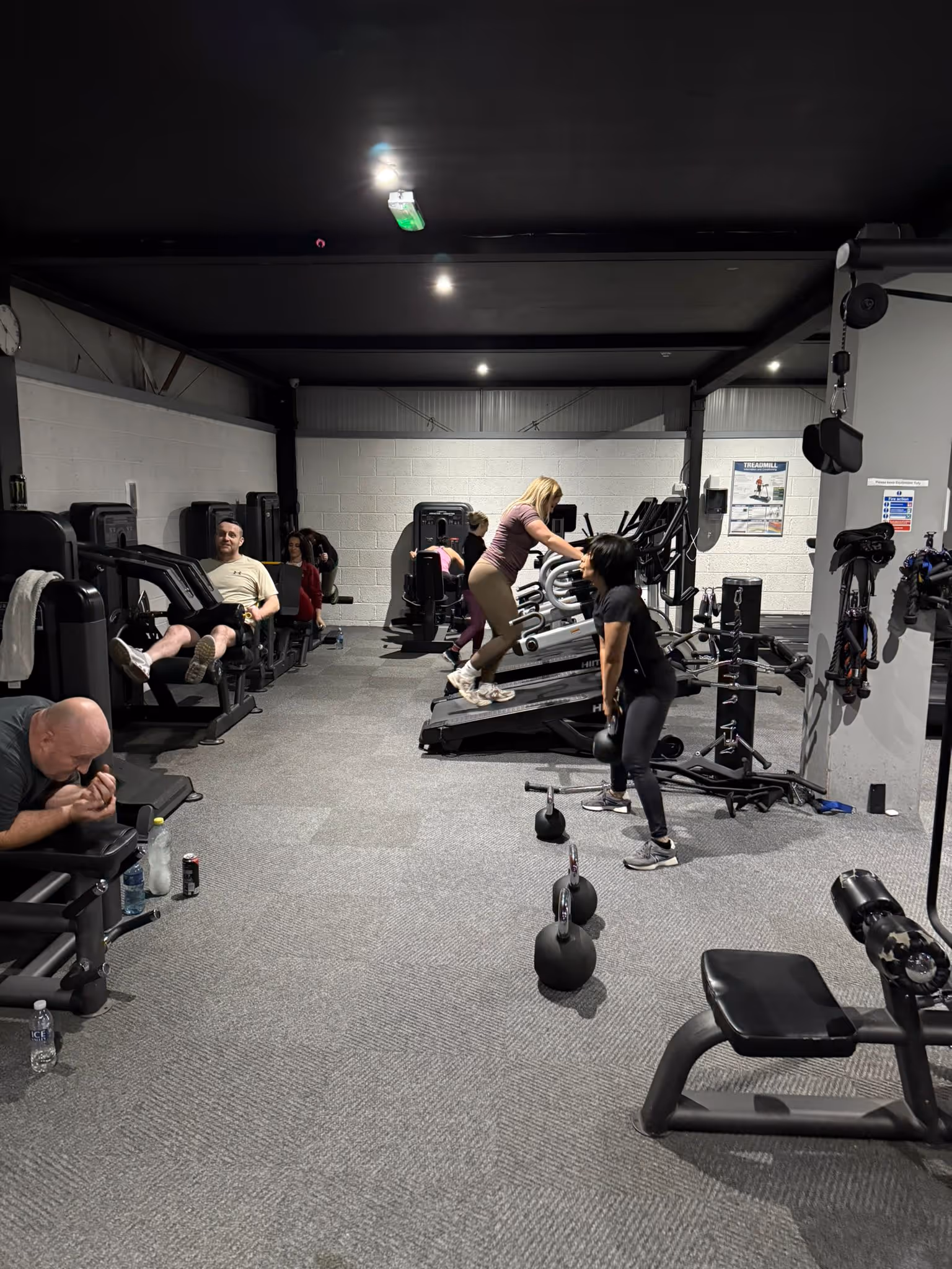 Members training at Magee's Health & Fitness in Belfast, using cardio machines, strength machines and kettlebells during a group workout