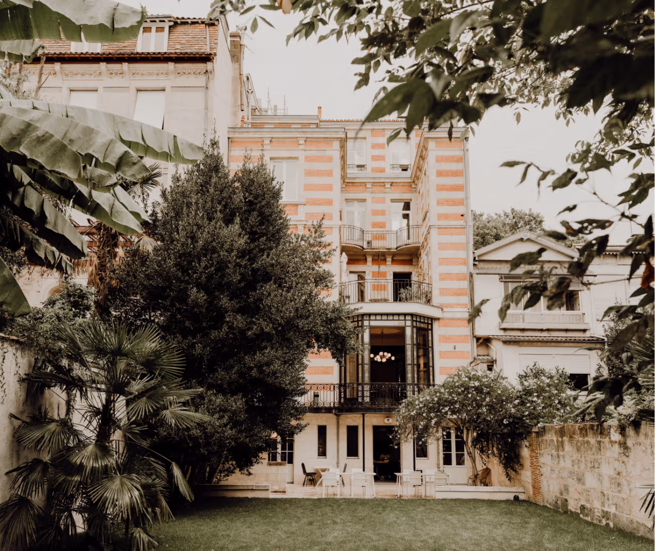 ue de l'extérieur du bâtiment de l'École du Septième Art, une grande maison historique avec des bandes de briques rouges, entourée d'un jardin verdoyant et de verdure.