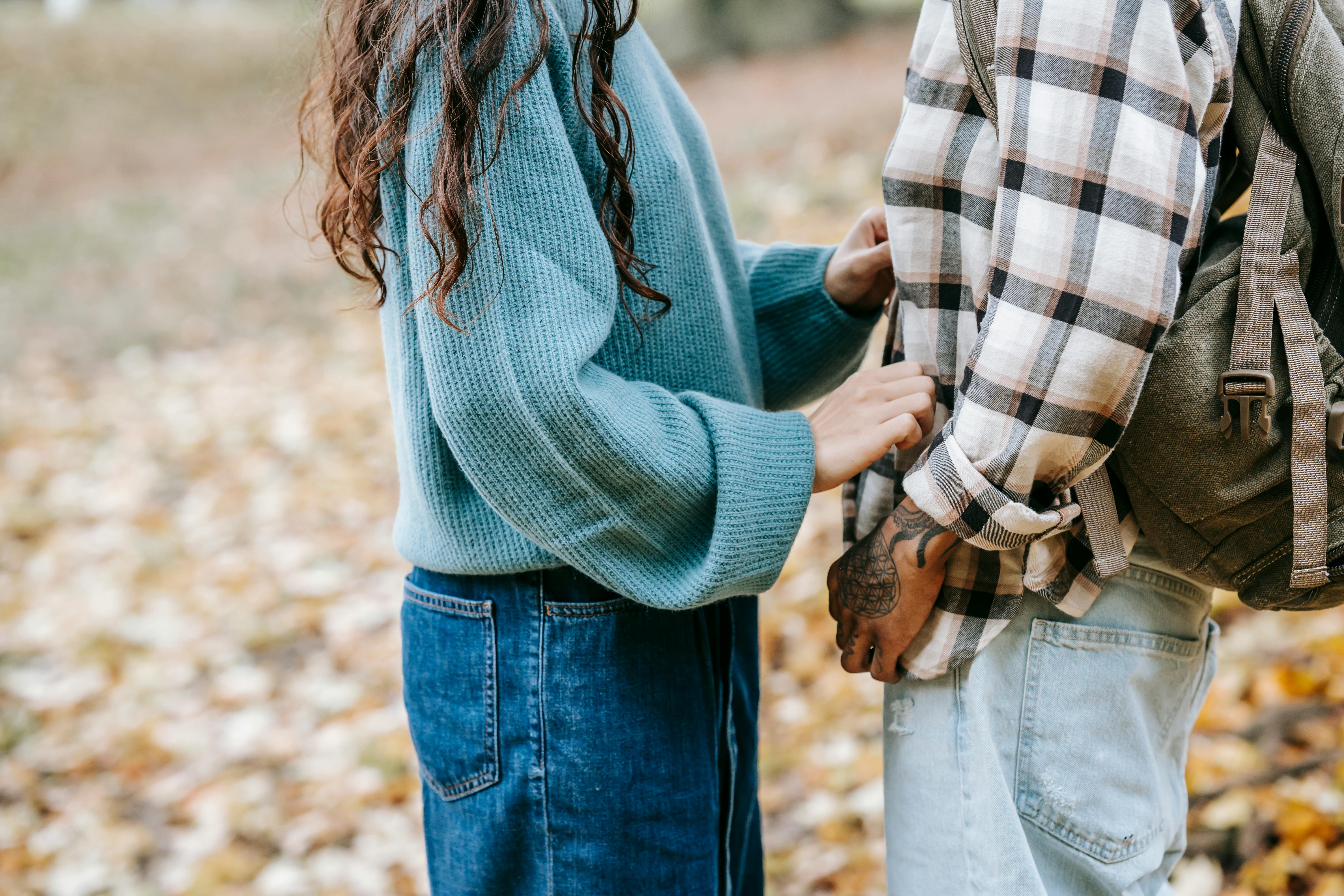 A couple facing each other against a backdrop of fallen autumn leaves. 