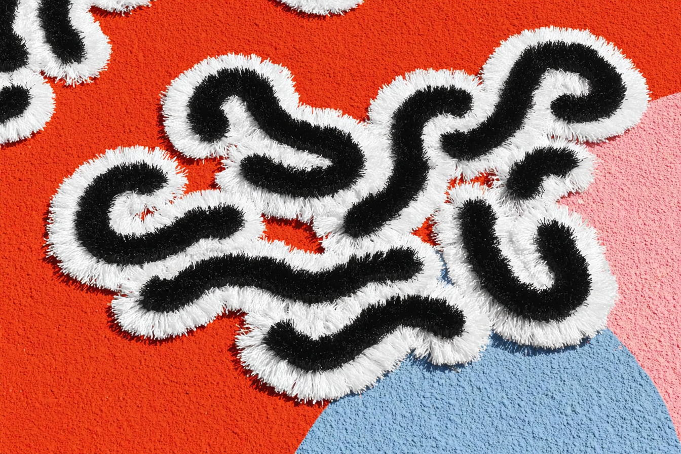 Textured rug with black and white abstract squiggle patterns on a background of red, blue, and pink shapes.