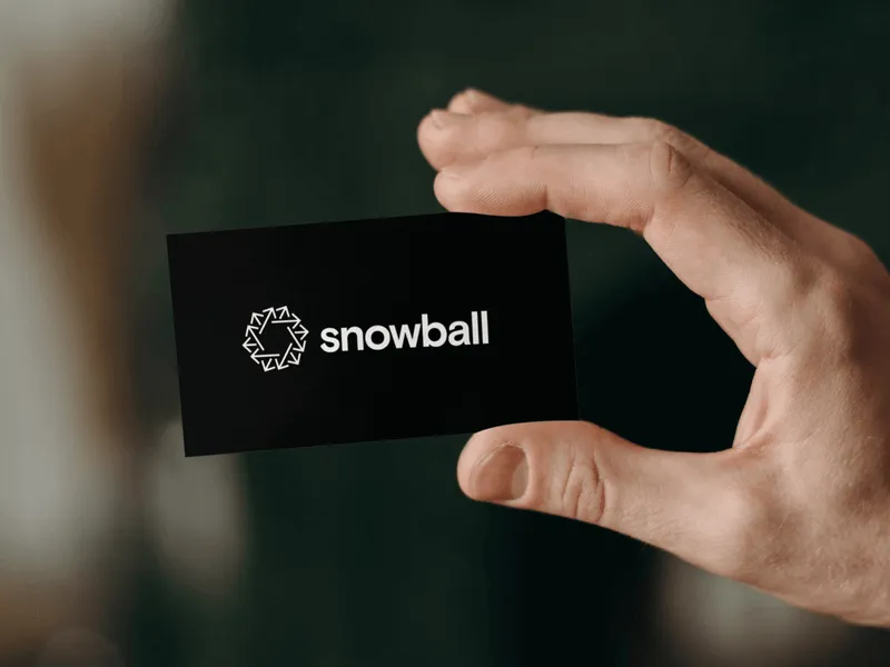 Photograph of a hand holding a black business card with Snowball's logo in white