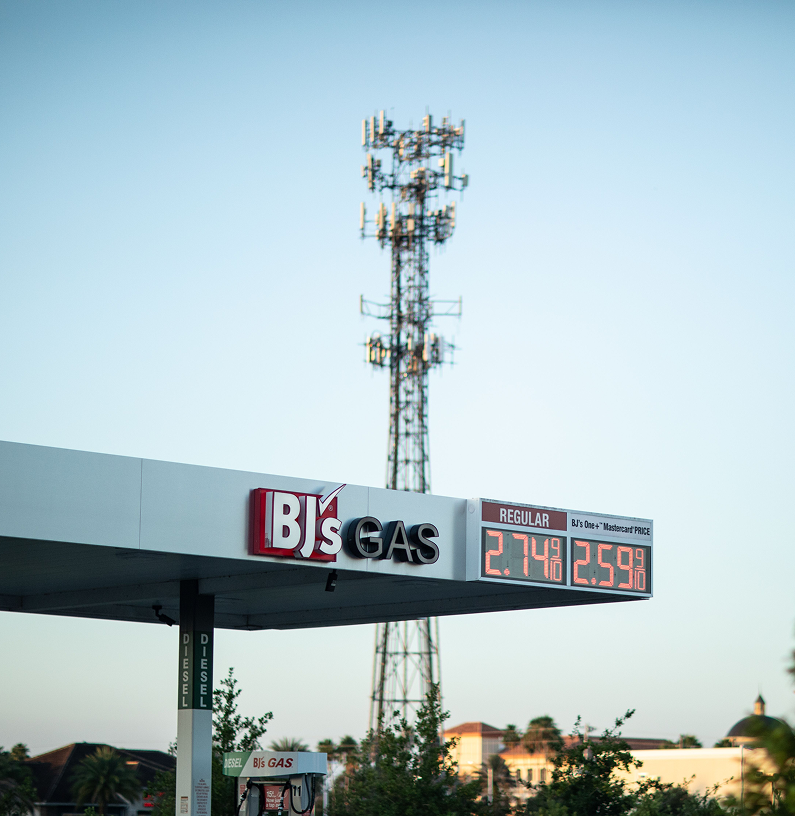 Gas station price sign showing regular gasoline prices at $2.74 and $2.59 with a communication tower in the background.